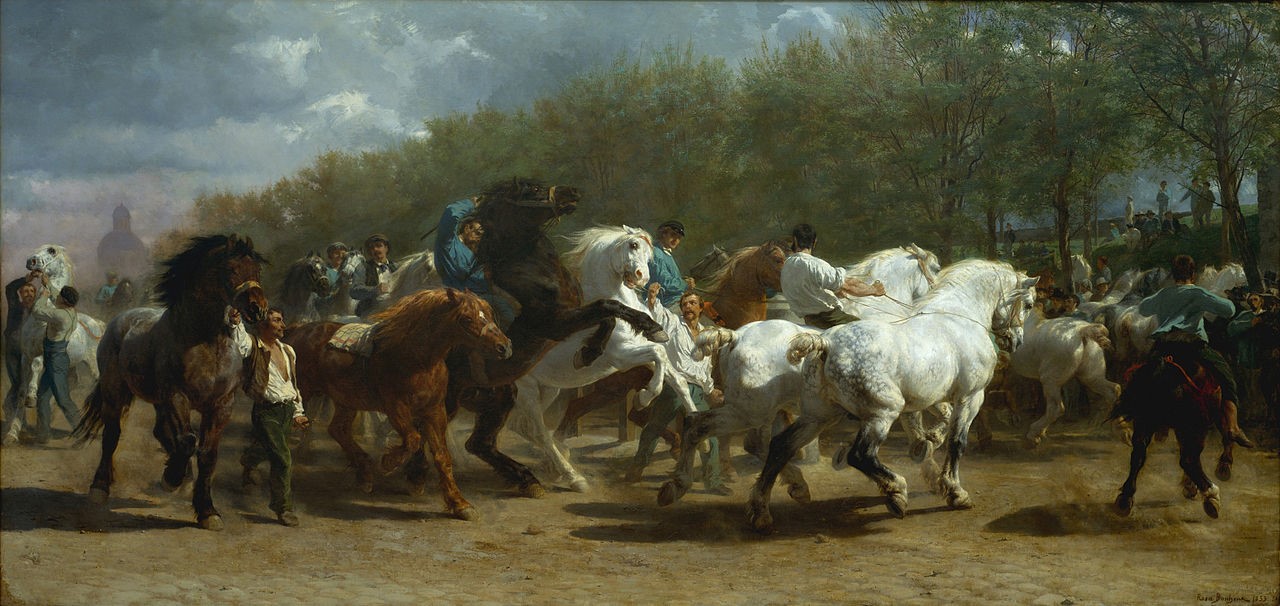 Oil painting depicting a horse fair with horses in different colours including brown and white being ridden or walked by men. The horses look to be running and changing direction. In the background is a blue cloudy sky, a building and a row of trees.